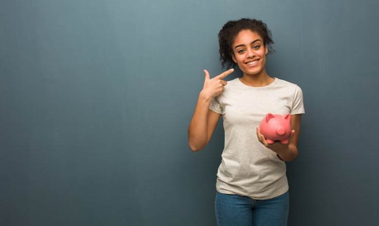 woman holding a piggy bank and pointing to her smile