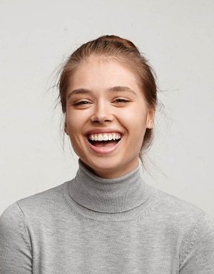 a woman in Orange smiling with her new dental bridge