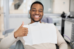 Male dental patient smiling and giving a thumbs up