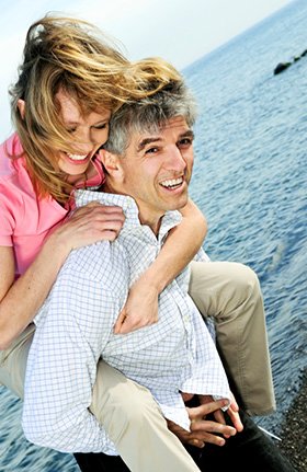 Man and woman smiling after replacing teeth with dental implants in Orange California