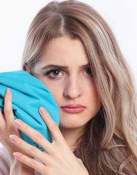 woman using cold compress after dental implant surgery in Orange
