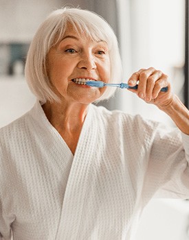 woman brushing teeth in bathroom mirror
