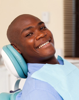Man in dental chair smiling after getting dental implants in Orange